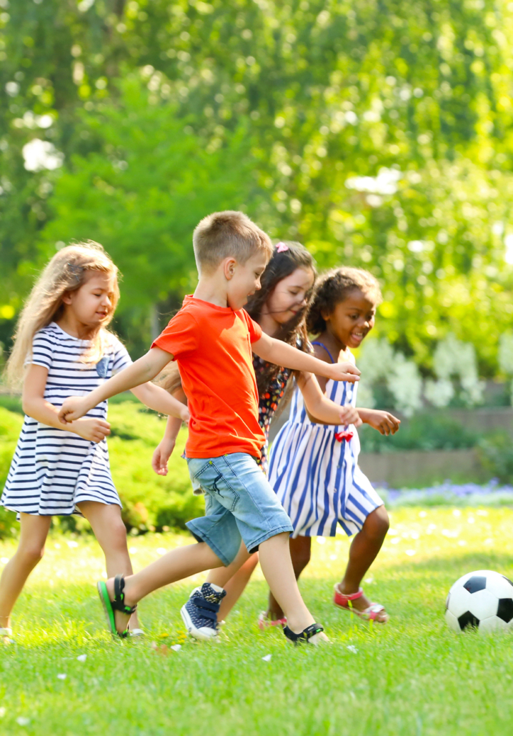 Cute little children playing football outdoors